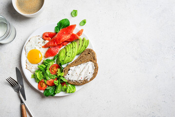 Healthy breakfast - fried egg, salmon, avocado and green salad