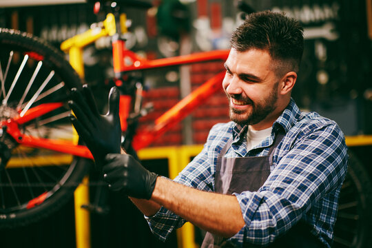 Smiling bicycle mechanic wearing black gloves in workshop