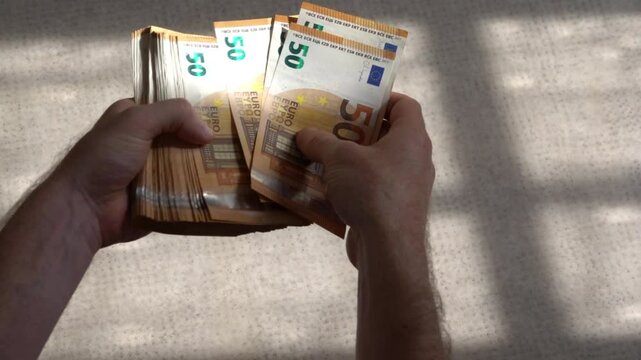 Beaucoup de billets de 50 euros tenus en mains
