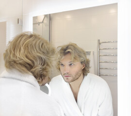 morning routine, young man looking in mirror in bathroom