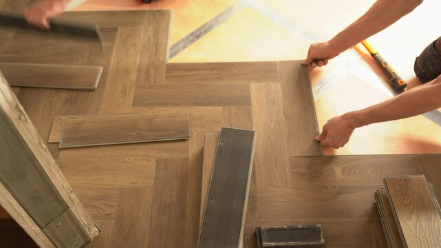 Two workers were laying quartz vinyl flooring during the renovation of an apartment or house. Laminate or quartz vinyl coating in dark color with a wood pattern. High quality 4k footage