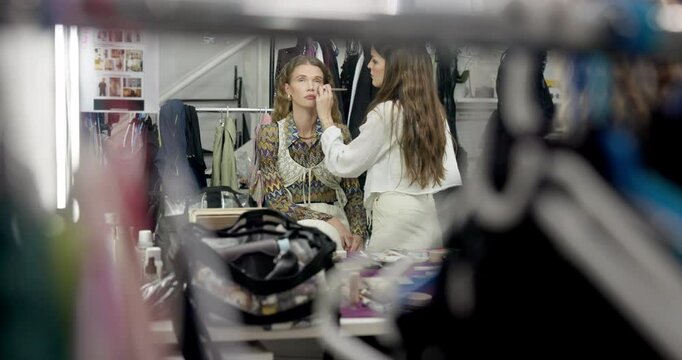 Women, makeup artist and makeover for model, cosmetics and preparing for photoshoot, glow and studio. Production, agency and stylist with brush for set, behind the scenes and people with equipment