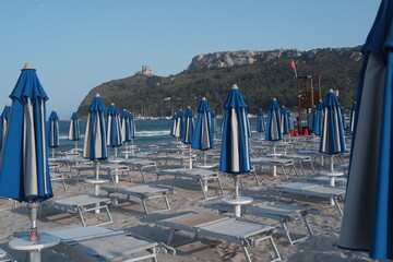 Closed umbrellas on sandy beach in Sardinia, Poetto shore with summer mood and calm coastal atmosphere