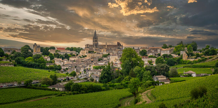 Springtime brings vibrant greenery to the Bordeaux vineyards surrounding the charming village of Saint-Emilion, showcasing picturesque hills and historical architecture.