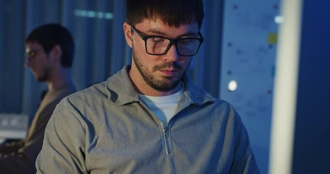 Team adult male freelance developer work late typing write prompt AI bot app program nomad terminal code at office night. Artificial intelligence dashboard, robotics, user interface, machine learning.