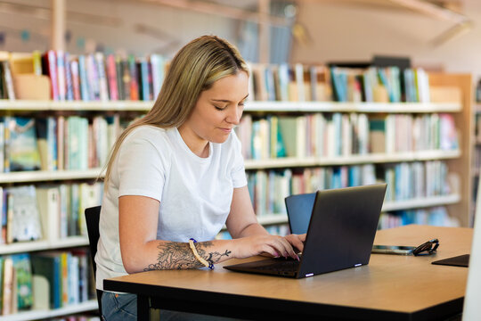 Young Aboriginal Australian woman in her twenties at library using laptop to study tafe course