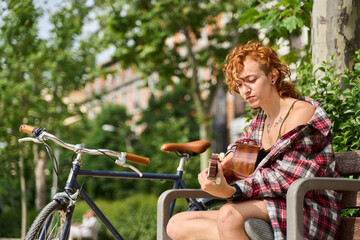Obraz premium Young woman playing guitar in a city park