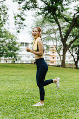 Jogging woman in athletic wear urban park fitness activity green environment dynamic viewpoint healthy lifestyle