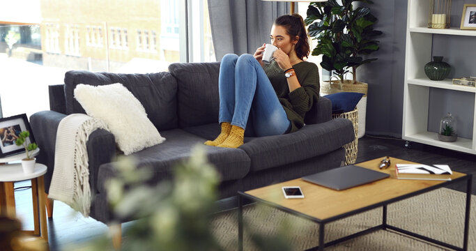 Woman, relax and drinking coffee on sofa for morning, beverage or warm comfort at home. Female person, cup or thinking with mug of caffeine on living room couch for daydreaming or wonder at house