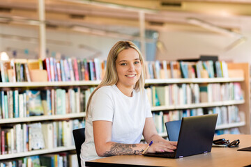 portrait of Aboriginal Australian woman in her twenties at library using laptop to study tafe course