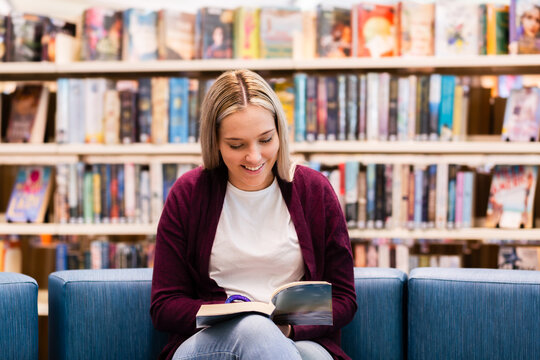 Young Australian woman in her twenties in library reading a fiction book