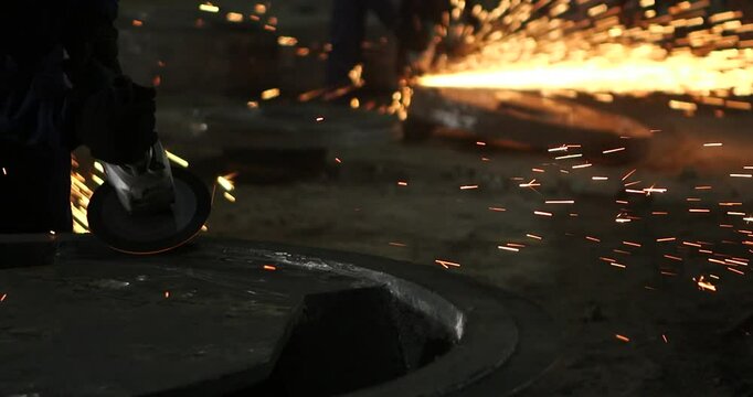 Male hand cuts off pieces of water pipe with angle grinder. Cutting of a steel with splashes of sparks at construction site. Sparks during cutting of metal angle grinder