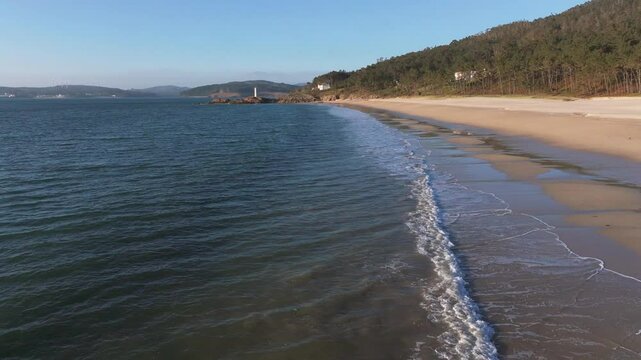 Flying Over The Waves At Praia do Lago With Fazo baliza do Lago In The Background In Muxia, A Coru&ntilde;a, Spain. - aerial shot