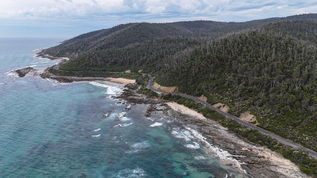 Aerial of road at bottom of mountains next to ocean