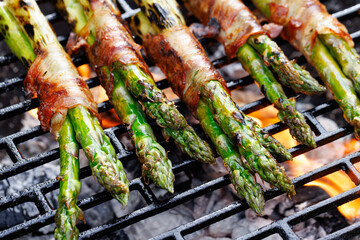 Grilled green asparagus wrapped in bacon on a cast iron grill, close-up view