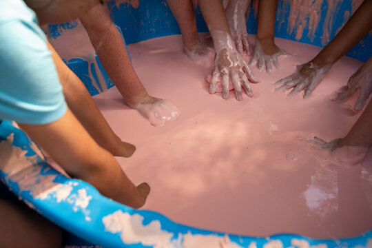 Science experiment with children dipping hands into oobleck, cornstarch and water mixture