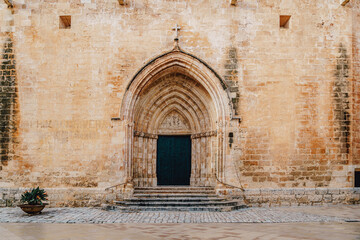 Gothic entrance of the Ciutadella de Menorca Cathedral are presented, featuring its iconic archway and historic stone. This prominent religious landmark is a part of Menorca cultural heritage