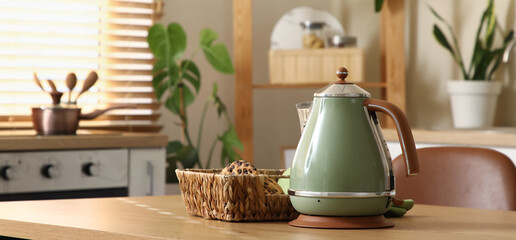 Electric kettle with basket of cookies on table in kitchen