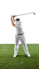 Golfer lifting club high for a strong swing while standing on green grass, dressed in classic attire and focused on ball against white backdrop. Concept of luxury sport, tournament, leisure