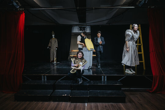 Fototapeta Young actors engaged in a dramatic performance on a stage setting. Theatrical costumes and props enhance the dynamic atmosphere, emphasizing creativity and artistic expression in a theater environment