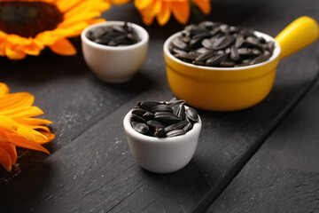Bowls with sunflower seeds on black background