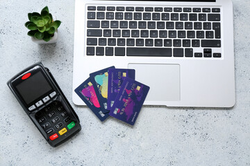 Laptop with payment terminal and credit cards on grunge grey background