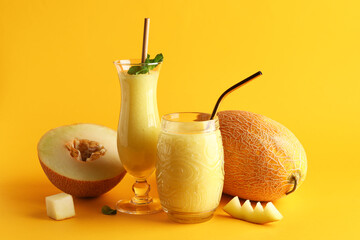 Glasses of tasty melon smoothie with mint on orange background
