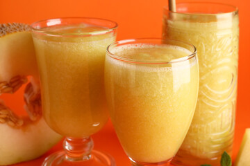 Glasses of tasty melon smoothie on orange background
