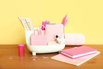 Holder with different stationery and notebooks on wooden desk