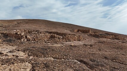Desert landscape with dry vegetation, mountains in the background, and a wide sky