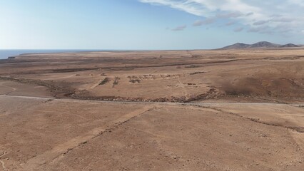 Desert landscape with dry vegetation, mountains in the background, and a wide sky