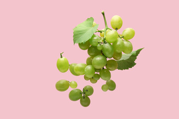 Flying sweet green grapes with leaves on pink background