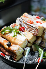 A close-up of French toast with berries and powdered sugar, creating a cozy breakfast scene.