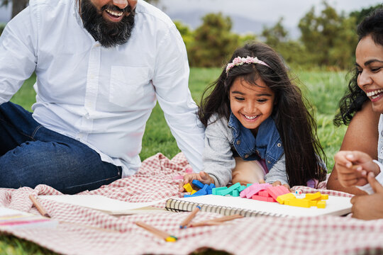Fototapeta Happy indian family having fun playing with their daughter outdoor at city park - Summer time and parenthood concept - Focus on kid face