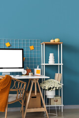 Interior of stylish home office with comfortable workplace, chrysanthemum flowers and pumpkins
