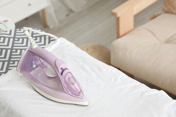 Electric iron on white t-shirt in room, closeup