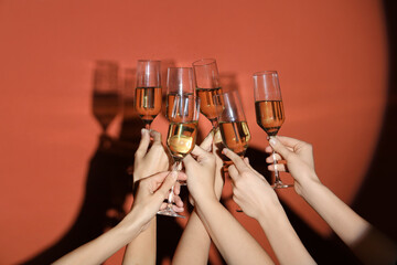 Female hands with glasses of champagne on orange background
