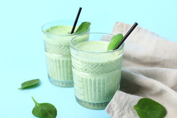 Glasses of fresh spinach smoothie on blue background