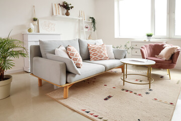Cozy sofa, armchair, coffee table and pictures in living room
