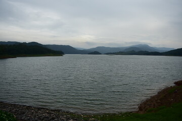 Umiam lake of Meghalaya, reflects, distant, hazy mountains under a soft sky.