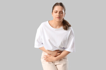 Young woman suffering from menstrual pain on light background