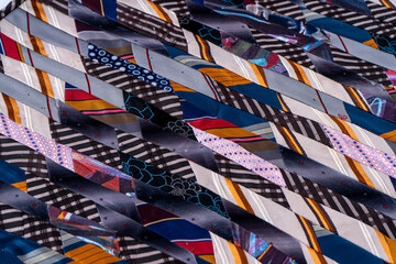 Patchwork background. A fragment of multi-colored pieces of fabric sewn together. Patchwork Quilt Made of Repurposed Neckties