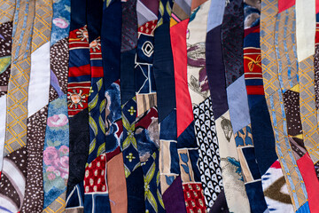 Colorful Quilted Patchwork Fabric background. A fragment of multi-colored pieces of fabric sewn together. Patchwork Quilt Made of Repurposed Neckties