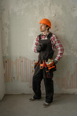 civil engineer in a helmet against the background of a gray concrete wall in an old apartment before renovation