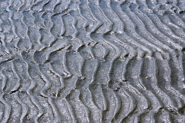 Graphic image depicting wavy lines created by the effect of the waves on a muddy sand beach on the coast of Puerto Piramide, in Argentine Patagonia.