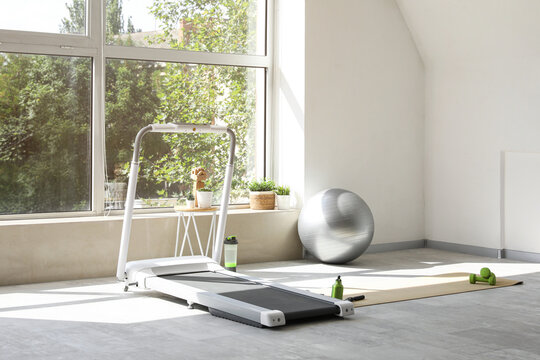 Interior of light gym with fitball and treadmill