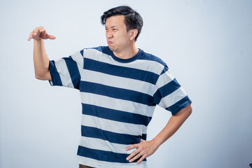 Asian man in navy and white striped t-shirt showing a disgusted expression with scrunched face and...