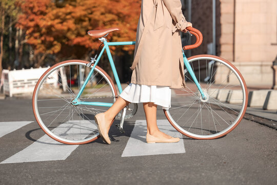 Fototapeta Young woman with bicycle walking across pedestrian crossing
