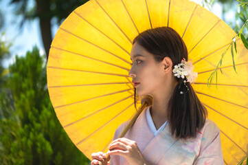 Pretty young Japanese woman in traditional kimono or yukata  clothing holding yellow umbrella