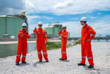 Group of refinery oil and gas engineers team in reflective jumpsuit and helmet working together in...